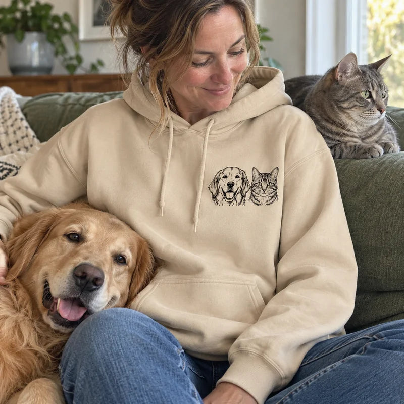 Sand hoodie with a golden retriever and tabby cat portrait together on the left chest, worn beside both pets