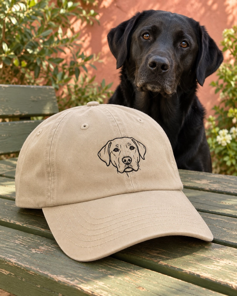 Stone dad hat with fine black Labrador portrait embroidery beside a black Labrador