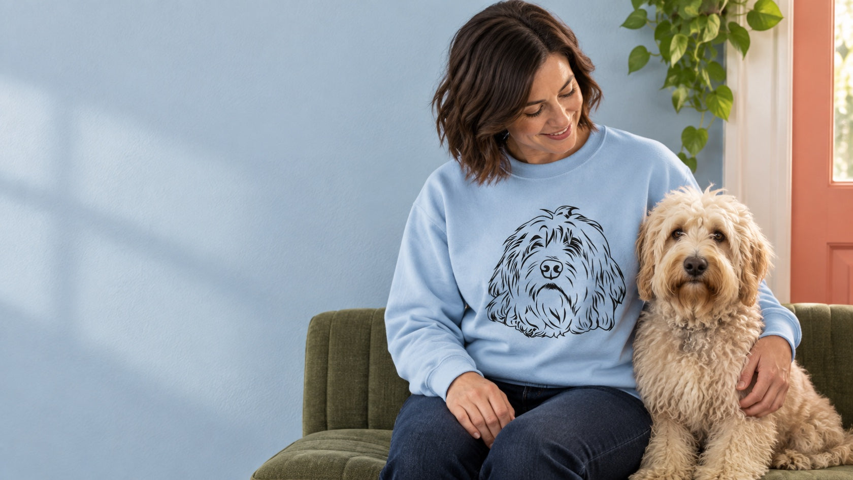 A light-blue custom pet sweatshirt with a shaggy dog's line-art portrait, worn beside the dog