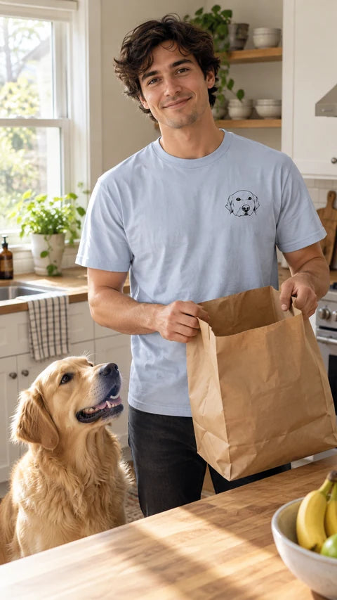 Light blue custom pet T-shirt with a golden retriever line-art portrait, worn beside a golden retriever in the kitchen