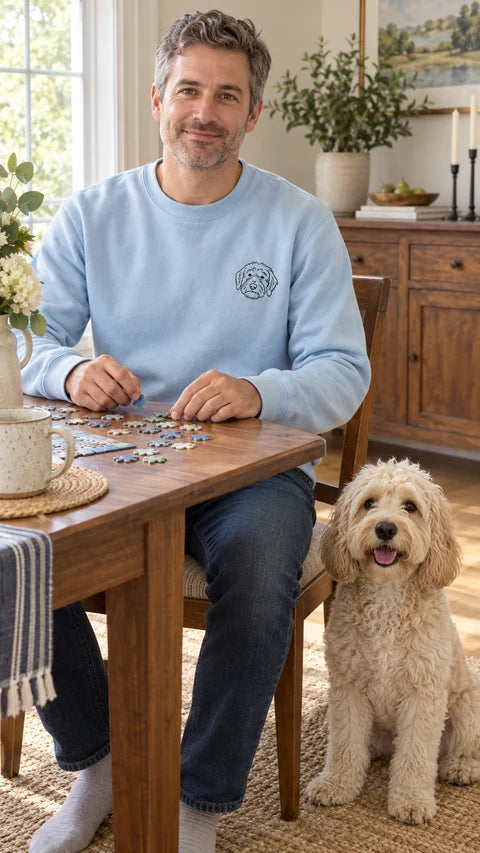 Light blue custom dog sweatshirt with a doodle line-art portrait, worn while working on a puzzle