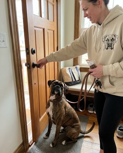Person wearing a custom dog portrait hoodie beside a boxer at the front door