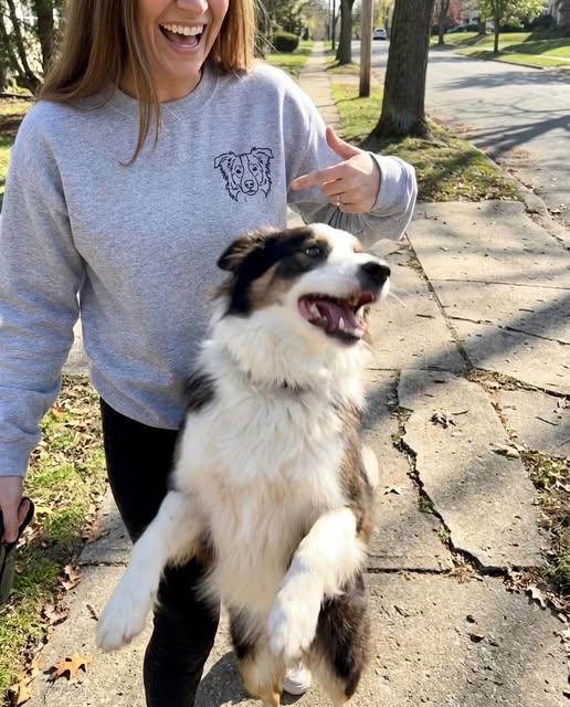 Person wearing a custom dog portrait sweatshirt beside their dog outdoors