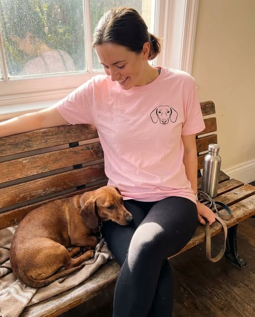 Person wearing a pink custom dog portrait T-shirt while sitting with their dog